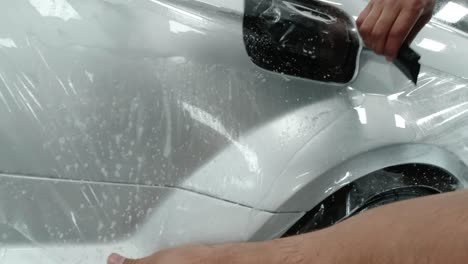 primer plano del proceso de instalación de ppf en un automóvil deportivo plateado