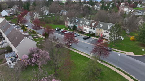 rising aerial of townhouse homes in usa town community during spring season with blooming trees