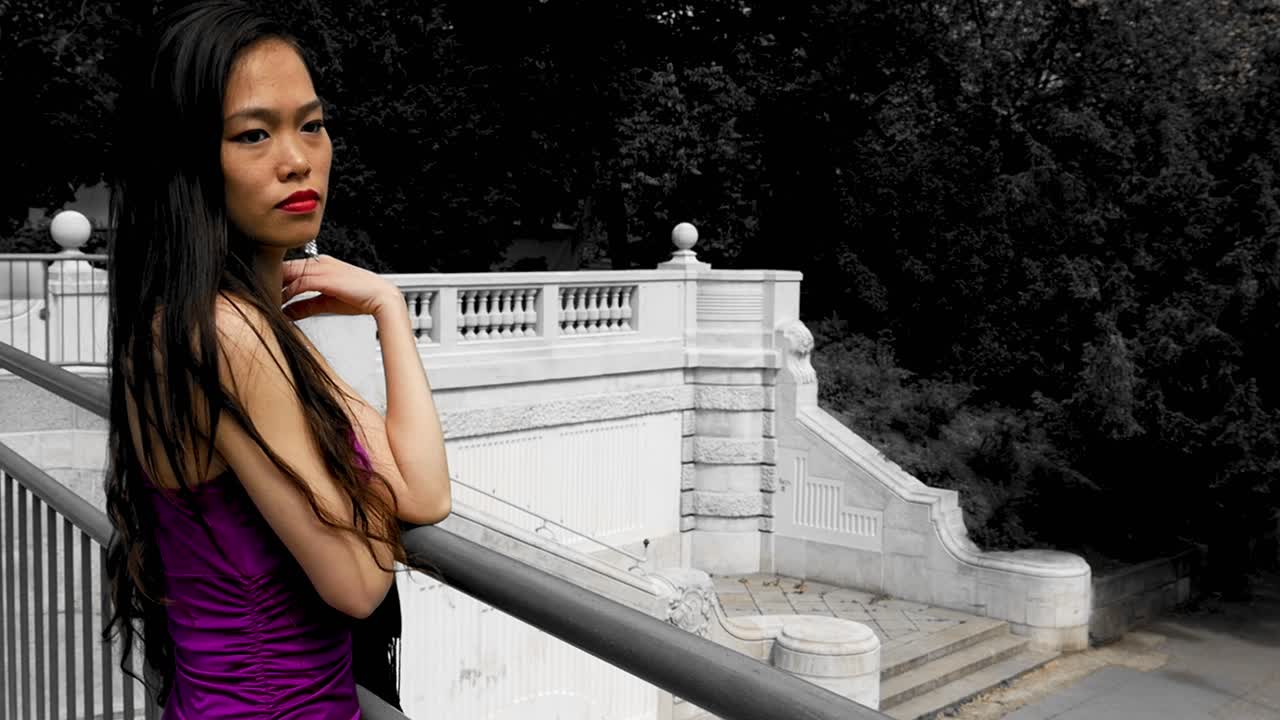 보라색 드레스를 입은 아시아 여성이 상하고 무언가를 관찰하고 있습니다.