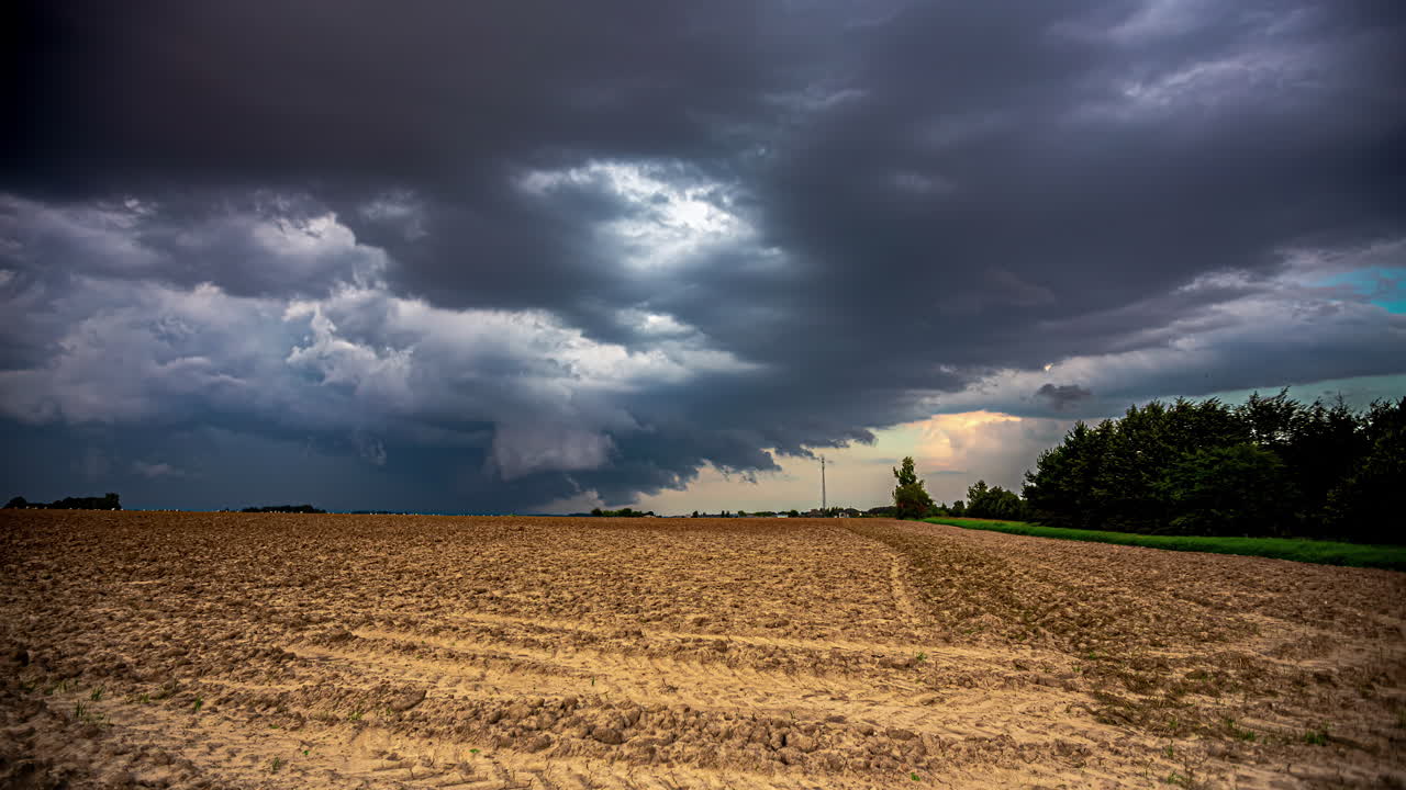 Storm clouds gather over a freshly harvested farmland field - dramatic cloudscape time lapse