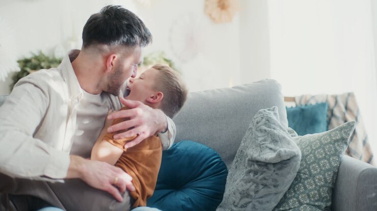 padre e figlio che giocano e fanno il solletico sul divano