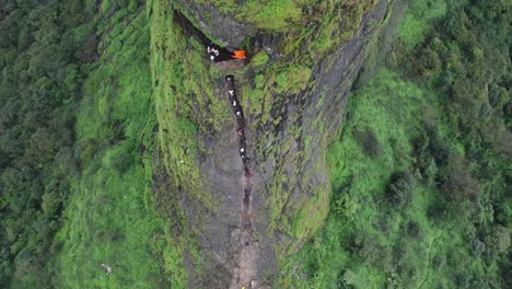 tomada con avión no tripulado de la antigua fortaleza de harihar con turistas bajando escaleras empinadas y verticales durante la caminata del monzón, harshewadi, nashik, maharashtra, india