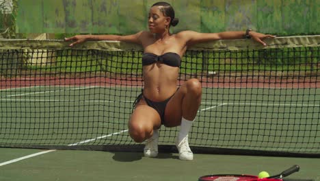 enjoying the sunshine, a young african girl exhibits her tennis prowess in a trendy bikini whike squating low angle