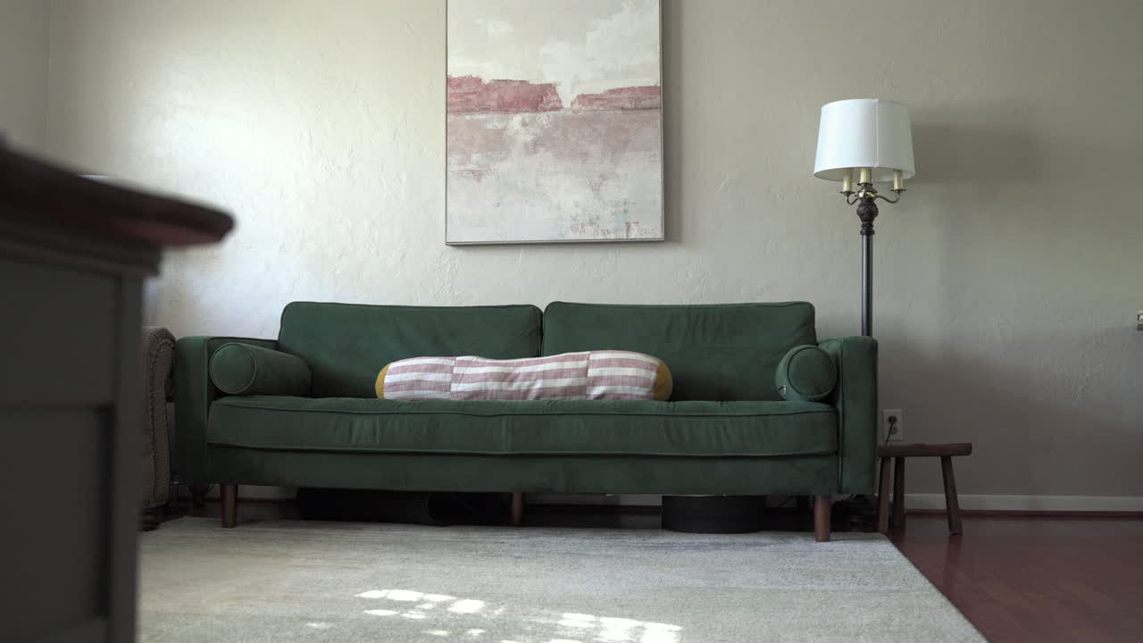 A rightward sliding shot of a modern living room featuring a green couch. The parallax effect adds depth and smooth motion to the scene.