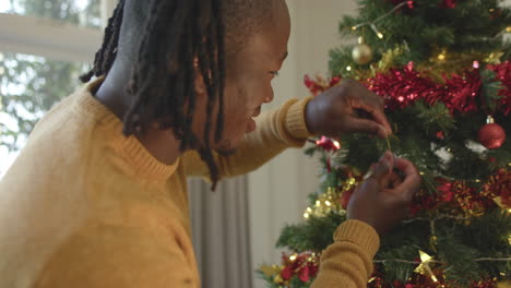 Feliz-Hombre-Afroamericano-Con-Rastas-Decorando-El-árbol-De-Navidad,-Cámara-Lenta