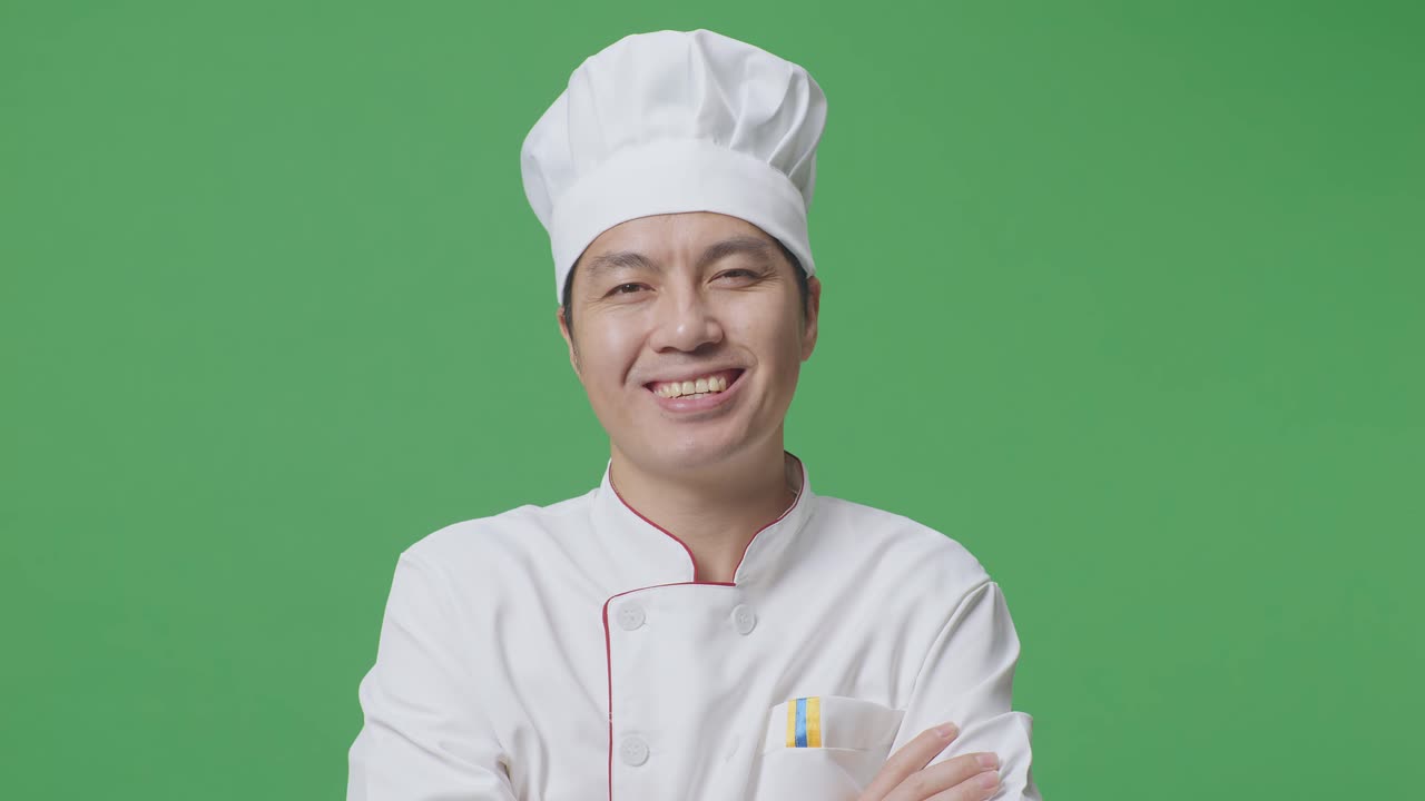 Close Up Of Asian Man Chef Smiling And Crossing His Arms To Camera While Standing In The Green Screen Background Studio