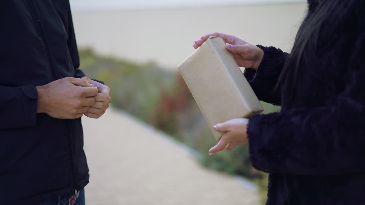 man gives a gift to his beloved woman and kisses her on the street on St. Valentine's Day