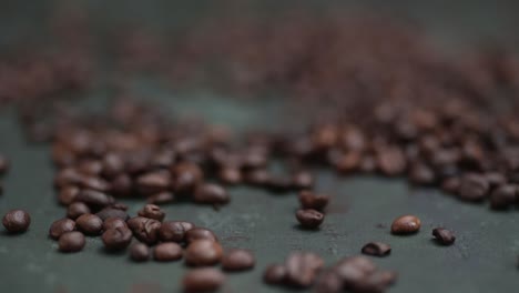 close-up push in through the coffee beans lying on the dark green background