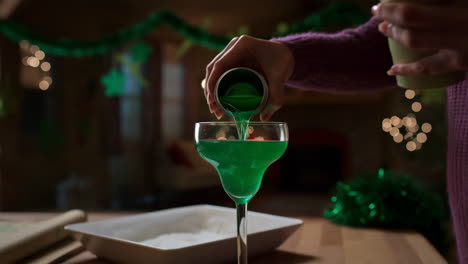pouring a festive green drink into a margarita glass