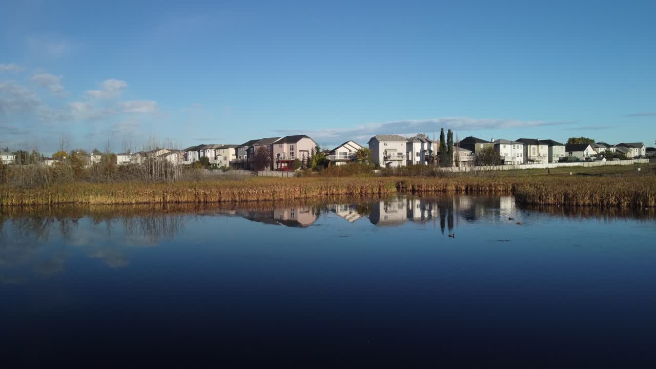 Neighbourhood next to a pond approached aerial drone