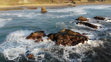 drone watches waves crash into a sea stack