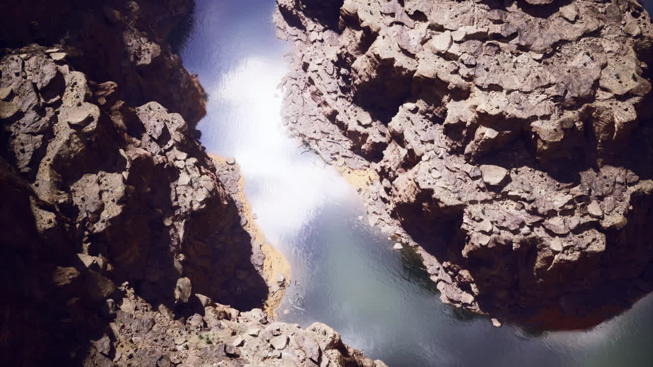 Rugged rock formations surround tranquil water in a secluded canyon area