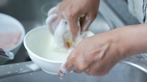 Women-cleaning-a-bowl-with-a-sponge