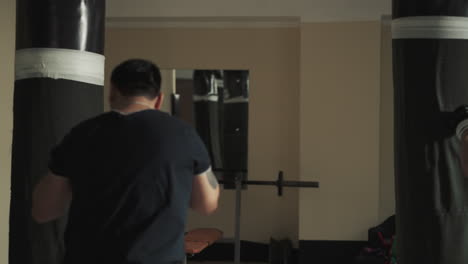 strong male boxers perform correct punching technique using special equipment and punching bags. group exercises in sports club. instruction from trainer to students