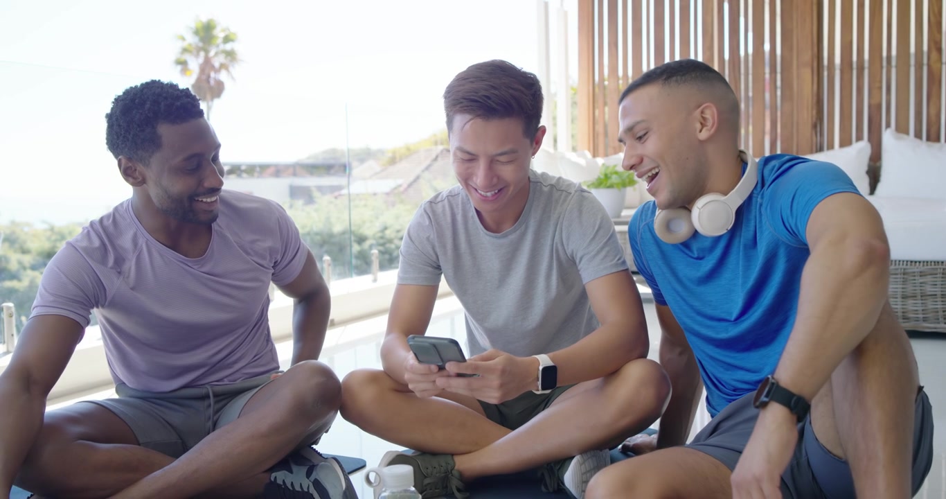 Diverse male friends in sportswear watching Asian man tapping phone and sharing clip on pool patio