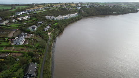 Vista-Aérea-De-La-Orilla-Del-Río-Kinsale-En-El-Río-Brandon,-Irlanda,-Casas-Residenciales-Y-Costa-Verde-En-Un-Día-De-Otoño-Cambiante,-Disparo-De-Drones