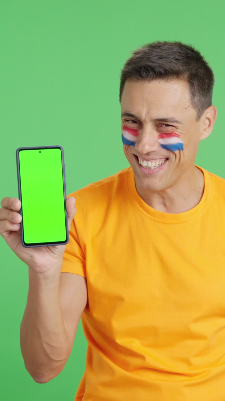 Dutch supporter looking at his mobile smiling and showing it