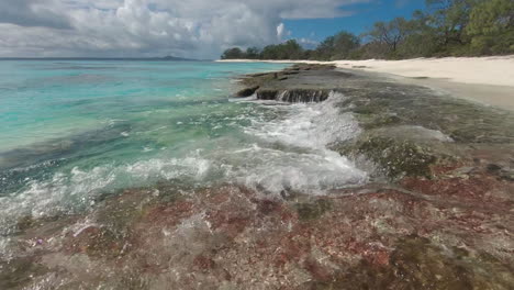 waves flow over rock formation on isle of pines beach, new caledonia