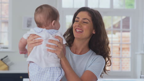 Mother-Playing-With-Baby-Son-At-Home-On-Kitchen-Worktop