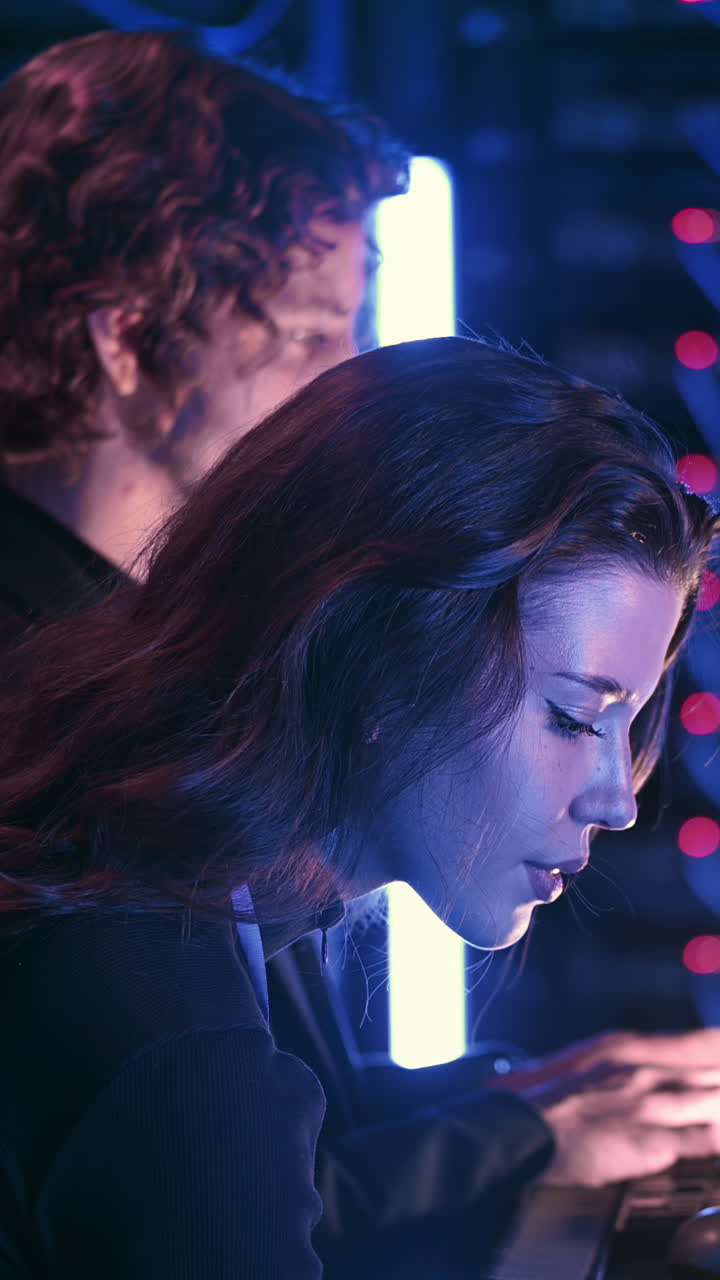 A man and a woman analysing data in a server room. Vertical