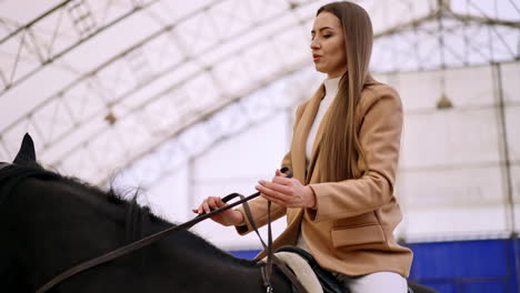 woman riding a horse in an indoor arena