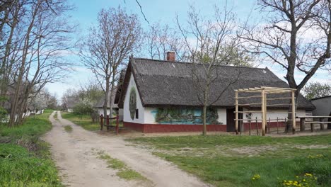 traditional thatched house with painted walls along a dirt road in spring
