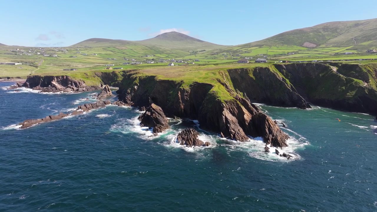 Maestose scogliere si ergono sopra il mare vibrante, con colline lussureggianti sullo sfondo. Ideale per documentari naturalistici o contenuti di viaggio.