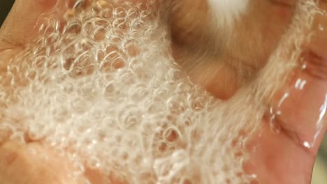 close-up of hands washing with running water and bubbles