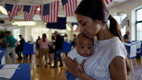 mother holding baby at a polling station with us flags