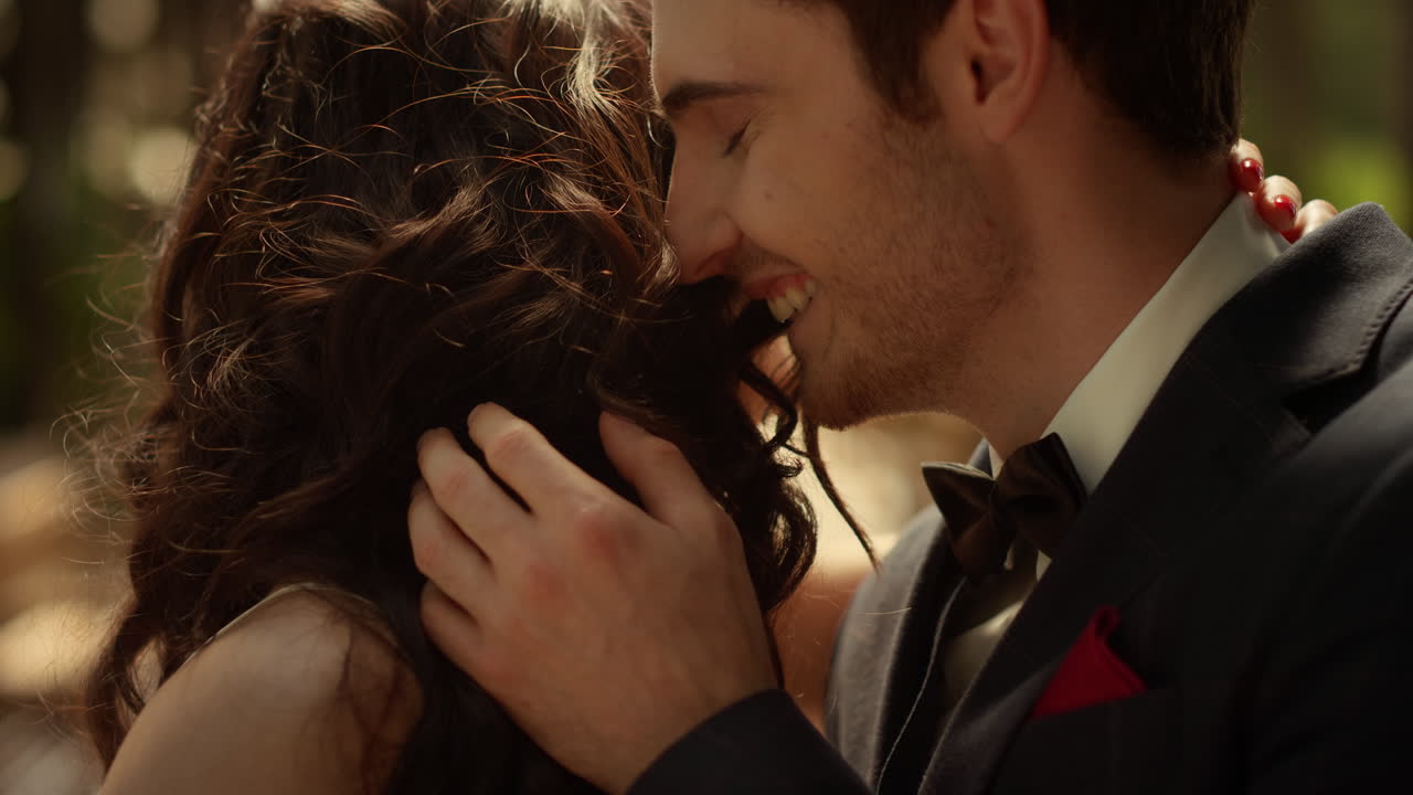 pareja alegre riendo en el jardín. hombre atractivo oliendo cabello de mujer al aire libre