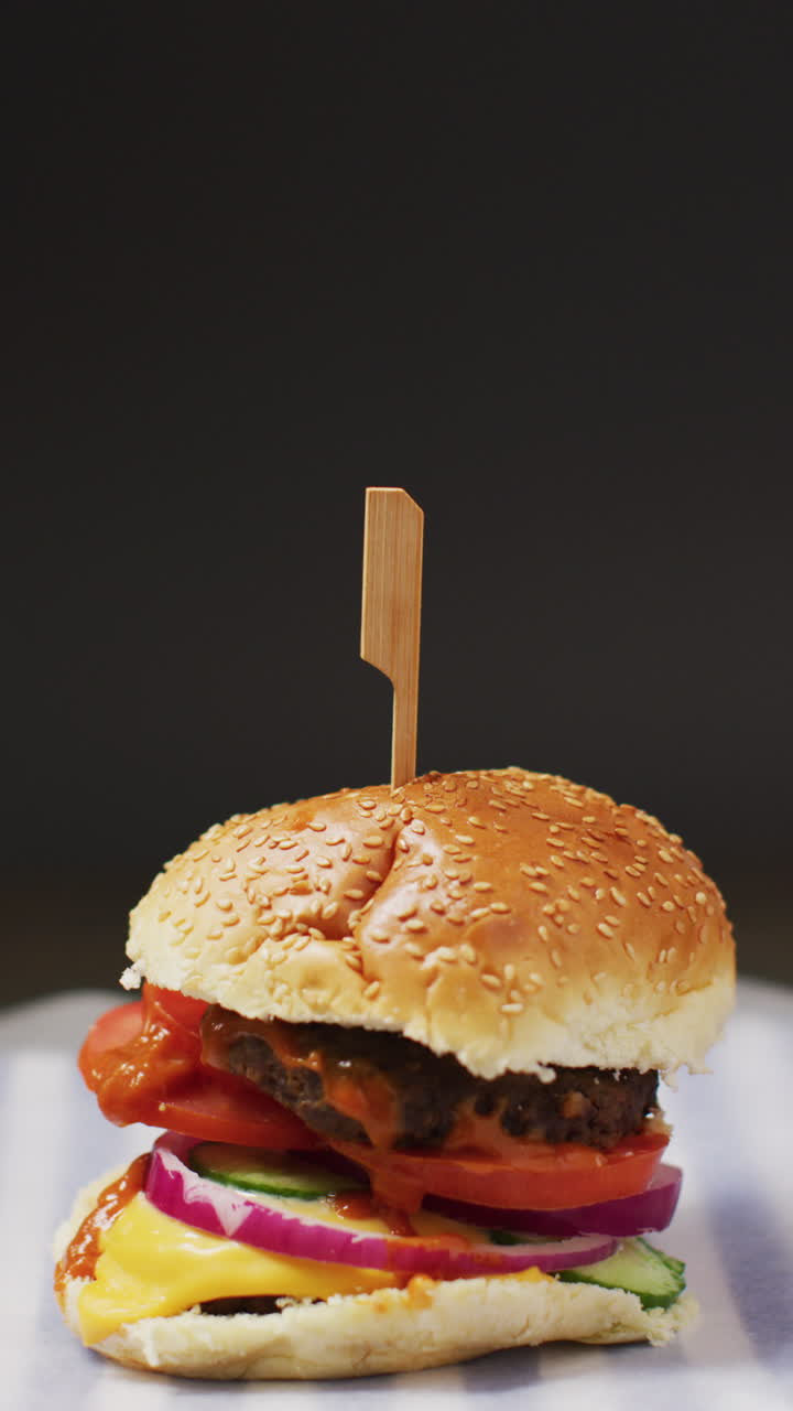 video vertical de una hamburguesa casera fresca con ensalada en un fondo gris