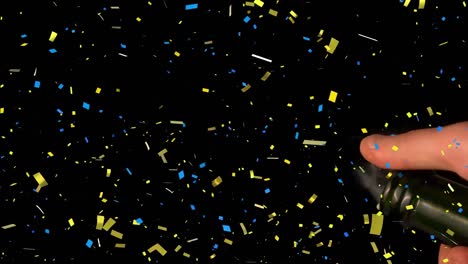 confetti falling over mid section of person opening a champagne bottle against black background