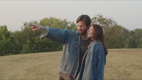 couple wearing denim point off screen at sunset in a park