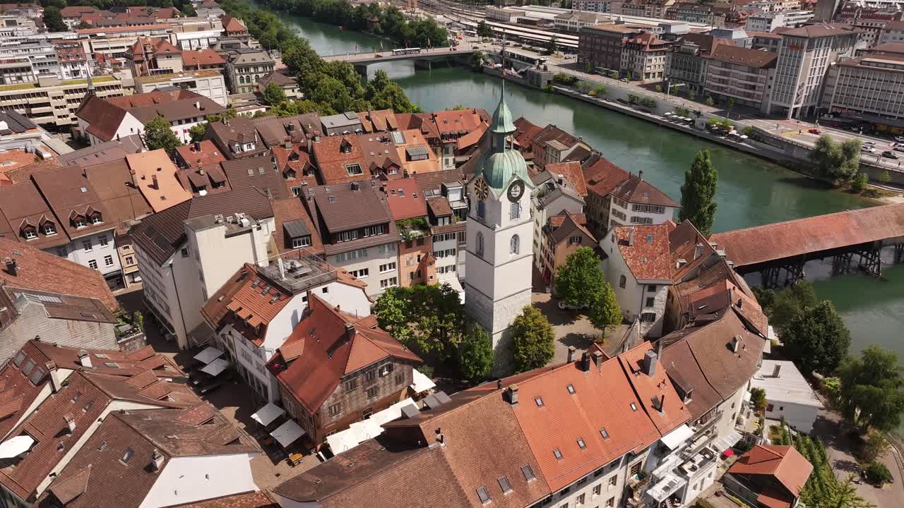 Drone panning shot of Olten's clock tower and rooftops beside the Aare River in Switzerland