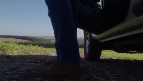 Farmer-steps-out-of-his-SUV-on-farm-road,-low-angle-shot