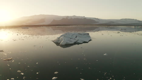 Reflexiones-Sobre-La-Laguna-Glaciar-Con-Iceberg-Iluminado-Por-La-Luz-Del-Sol-En-Jokusarlon,-Al-Sur-De-Islandia