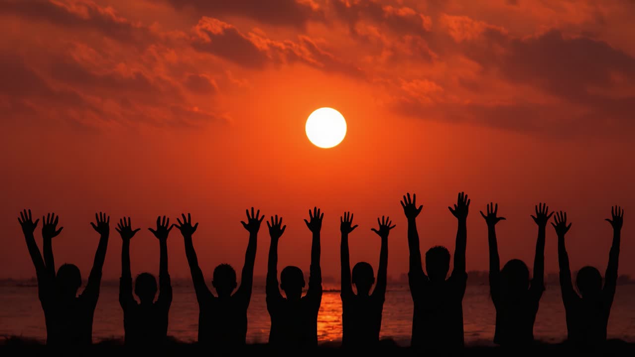 Silhouetted Figures Celebrating at Sunset with Outstretched Hands Against a Vibrant Orange and Red Sky Reflecting on Water