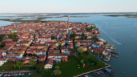 colorful houses and surrounding lagoon water at sunset in burano- island in the venetian lagoon, northern italy. wide aerial shot