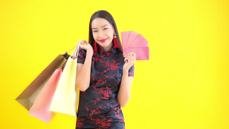 happy woman showing off colorful shopping bags and holding red cards or envelopes