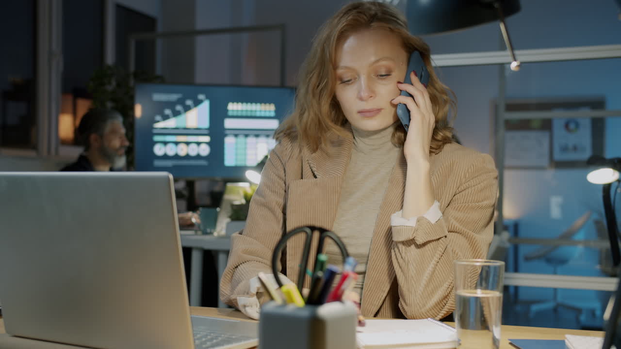 Kvinde i telefon på moderne kontor om natten