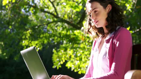 mujer hermosa usando computadora portátil en el jardín