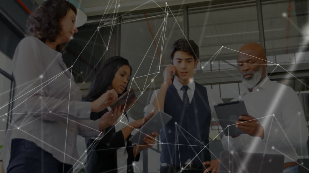 Colleagues collaborating in technology office, tapping tablets and navigating network overlay