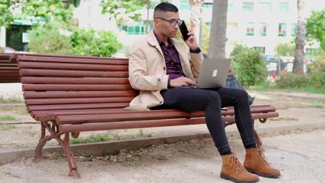 Un-Joven-Hombre-De-Negocios-Vestido-De-Moda-Hablando-Por-Teléfono-En-Un-Banco