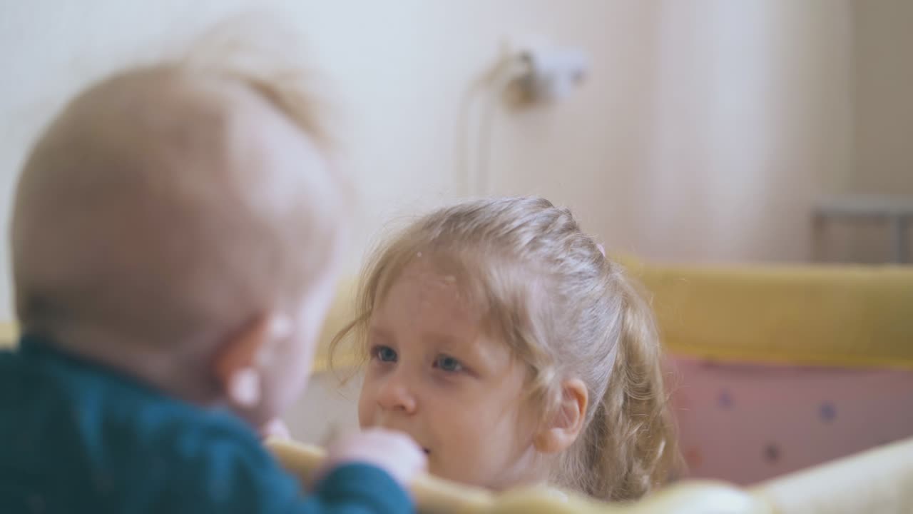작은 동생 은 집 에 있는 놀이터 에 숨어 있는 여동생 을 보고 있다