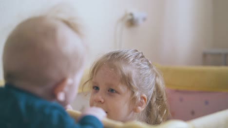 el hermano pequeño mira a la hermana escondida en el patio de recreo en casa