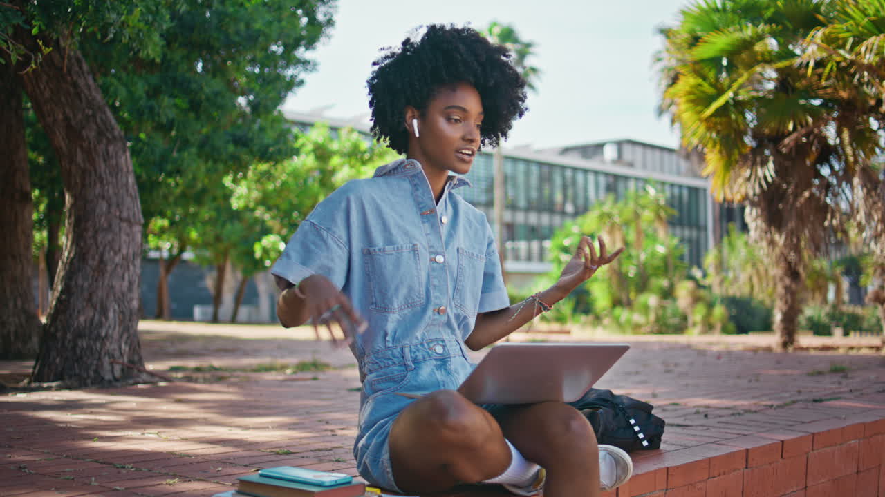 Student talking video call using laptop sitting street.  girl speaking