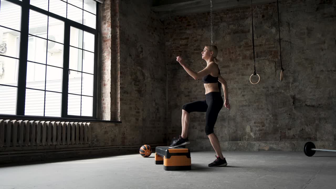 계단 플랫폼에서 점프하는 여성 느린 동작. 여성 다리 운동화 체육관에서 활발한 운동