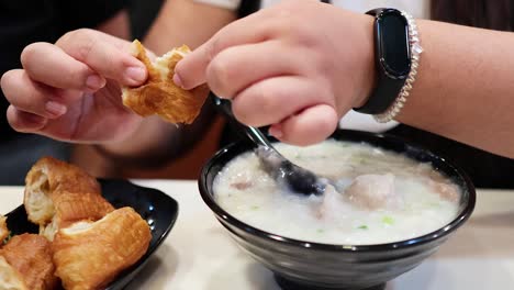 person eating congee with yau tze