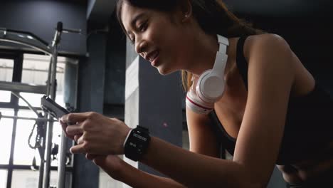 mujer sonriente alegre usando teléfono móvil en el gimnasio después del ejercicio