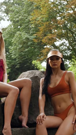 swimsuit models lounging on forest rocks, gimbal slow-motion shot